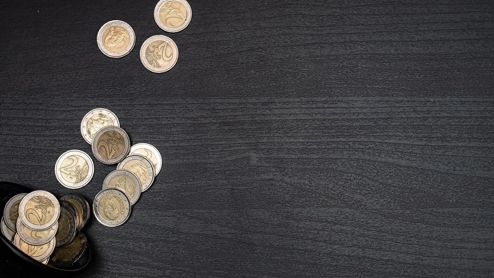 Euro-Münzen auf einem dunklen Holztisch