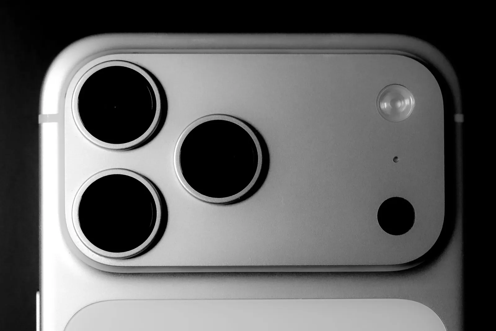 Nahaufnahme von drei Kameraobjektiven und dem Blitz auf der Rückseite eines silbernen Smartphones