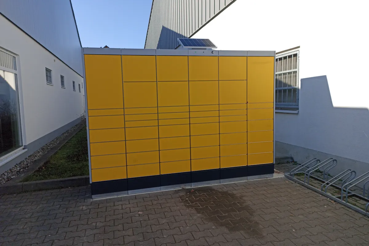 Gelbe Paketstation an einer Hauswand