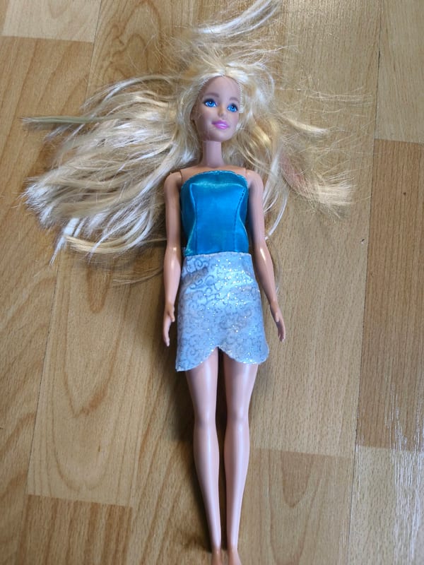 Puppe mit blonden Haaren und blau-silbernem Outfit