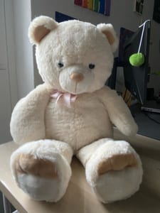 Großer cremefarbener Teddybär mit rosa Schleife